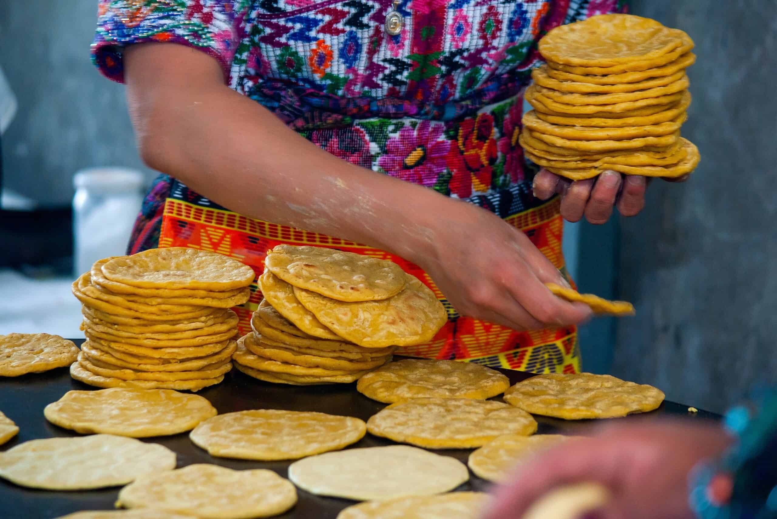 Woman making corn tortillas on metal plate